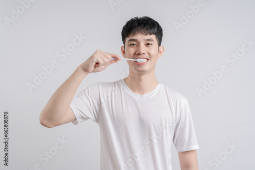 Handsome young man smiles happily and holding toothbrush.