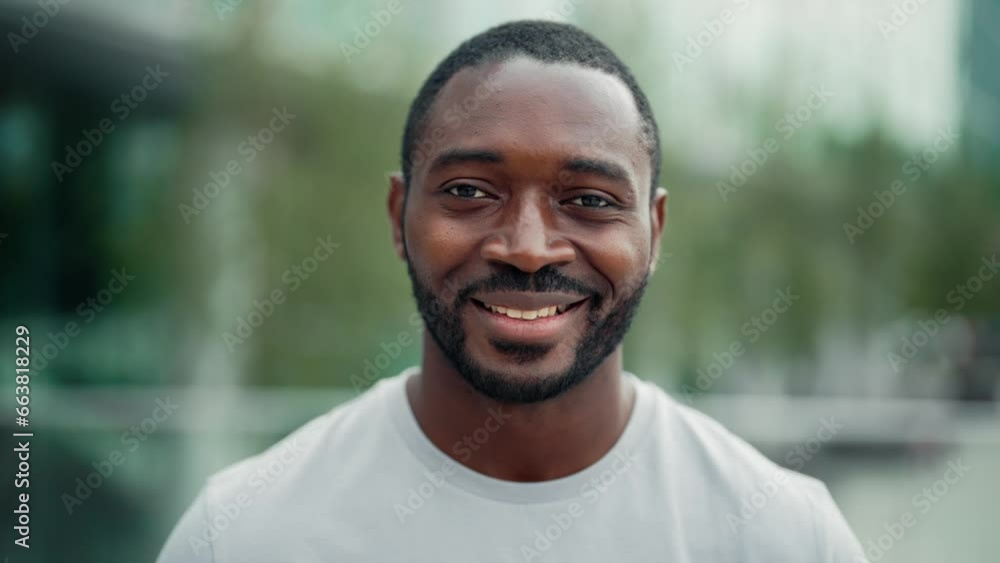 Portrait smiling positive african american bearded man on ctiy street looking at camera. Friendly charming guy on blur downtown background. Sincere human emotions, body language, good mood concept. Portrait smiling positive african american bearded man on ctiy street looking at camera. Friendly charming guy on blur downtown background. Sincere human emotions, body language, good mood concept.