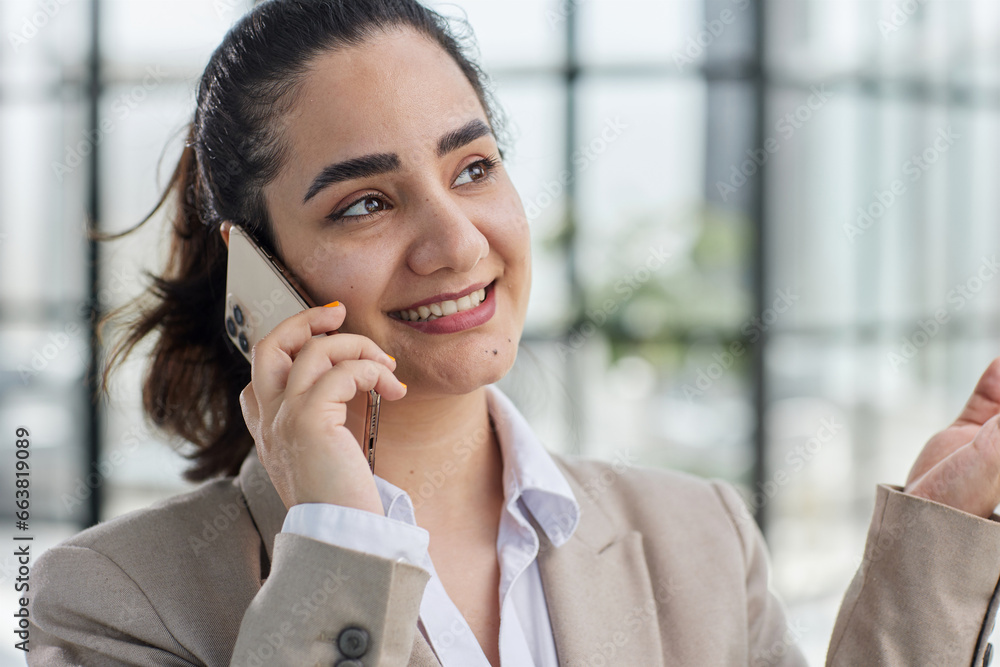 attractive woman talking on mobile phone while relaxing in office attractive woman talking on mobile phone while relaxing in office