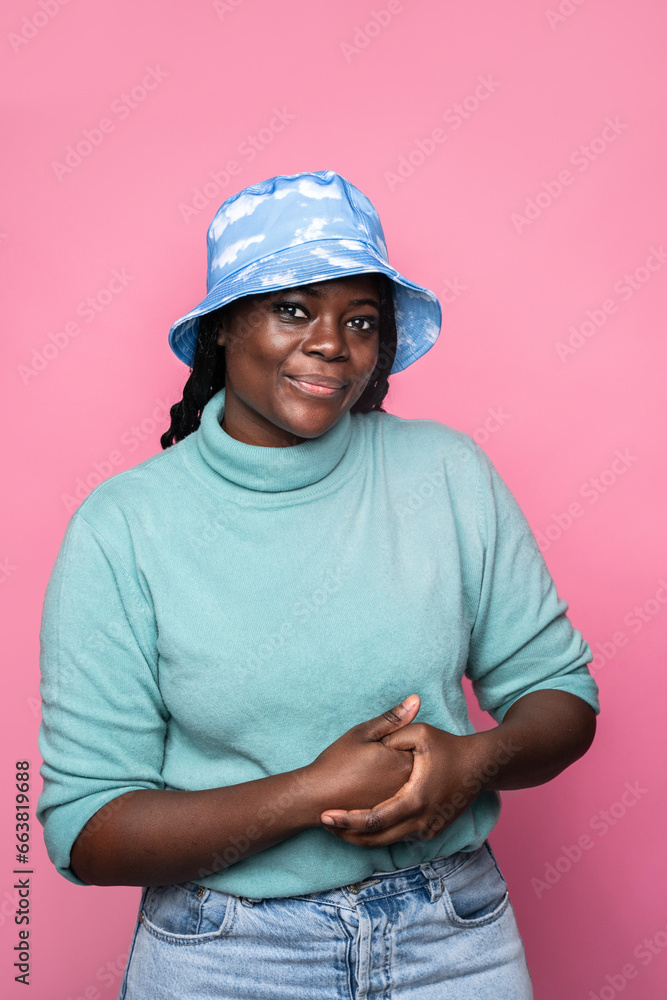 African woman in cloud-patterned hat against pink background African woman in cloud-patterned hat against pink background