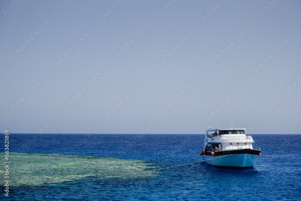white boat anchored on a beautiful green coral reef in blue water in the summer of egypt white boat anchored on a beautiful green coral reef in blue water in the summer of egypt