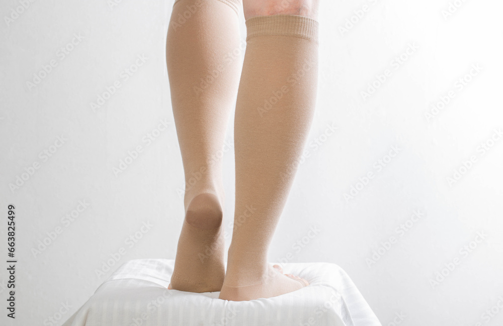 Female legs in compression stockings for varicose veins on the legs. White background