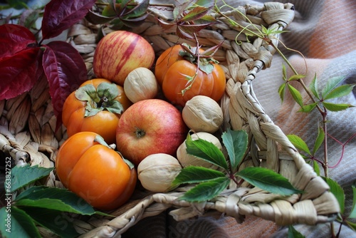 bright background. basket with apples  nuts and persimmons. beautiful background texture. juicy fruits. vitamins