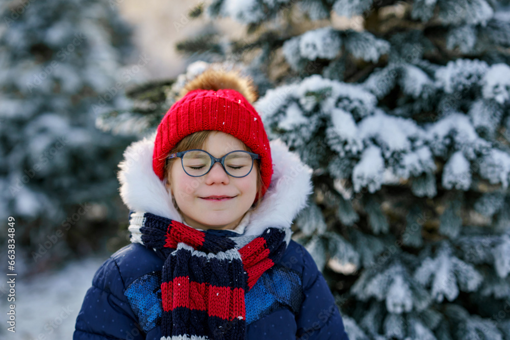 Obraz premium Small girl playing with snow. Happy preschool child in winter forest on snowy cold december day. Winter portrait of little preschooler in forest.
