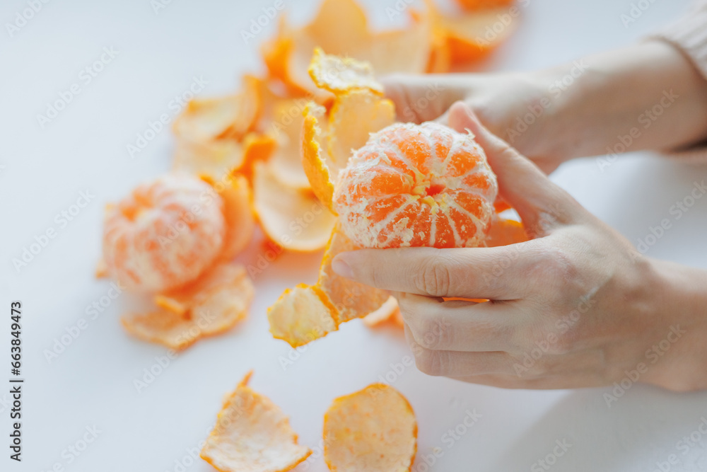 European woman cleans tangerines at home. citrus vitamins to boost immunity. new year Christmas, female cleaning juicy citrus fruits while relaxing indoors, eating vitamin C-rich food in winter season European woman cleans tangerines at home. citrus vitamins to boost immunity. new year Christmas, female cleaning juicy citrus fruits while relaxing indoors, eating vitamin C-rich food in winter season