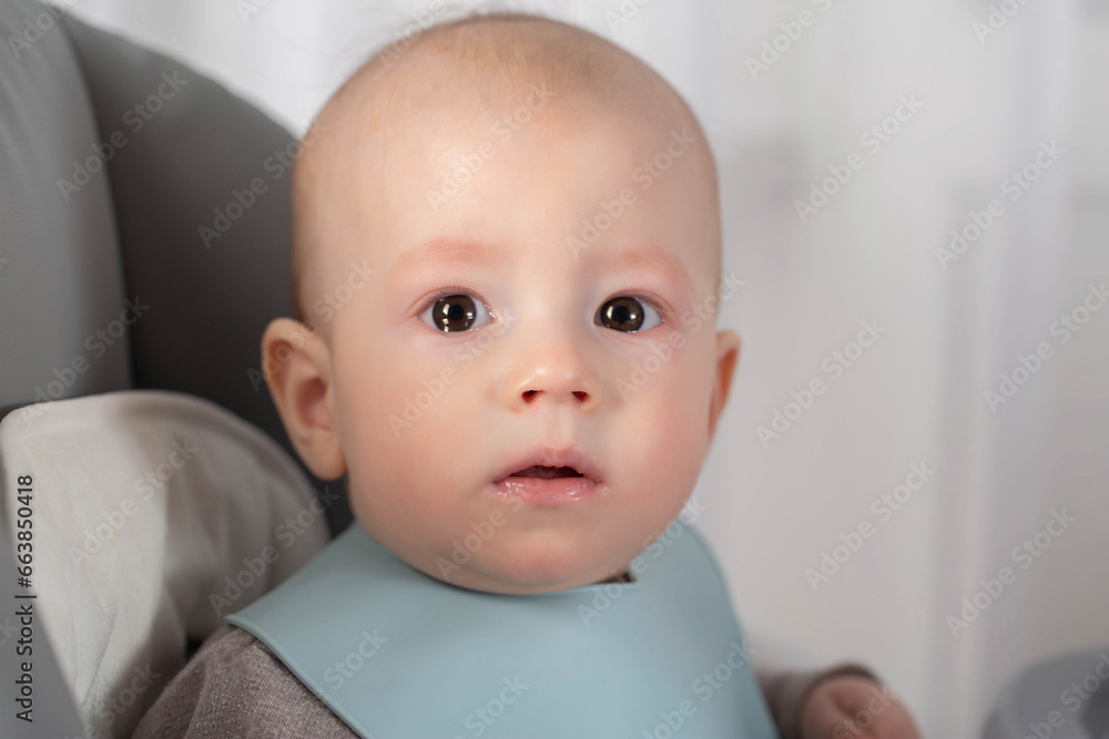 A small child at the age of 8 months is frightened and looks at the camera. The concept of taking medications in children with diseases. Copy space for text