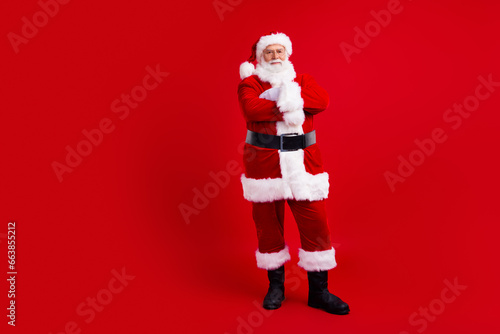 Photo of senior kind saint nicholas crossed arms standing empty space presenting new year season offer isolated on red color background