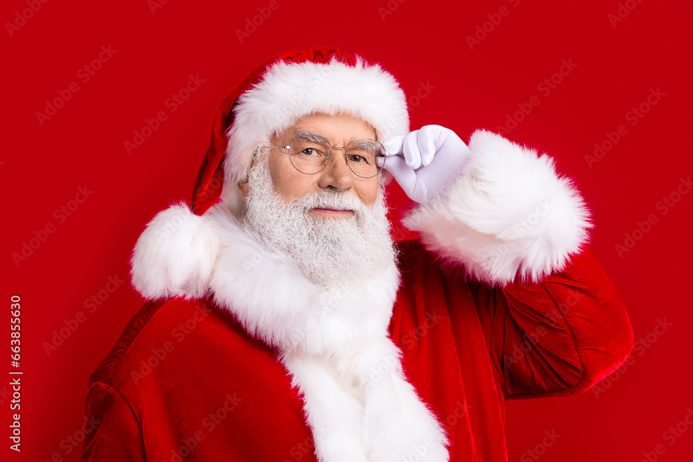 Photo of cheerful jolly santa claus wear white gloves fluffy pompom new year costume looking camera isolated on red color background