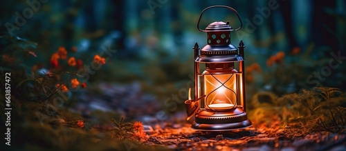Vintage gasoline oil lantern lamp burning with a soft glow light in a dark forest with a blur natural background photo