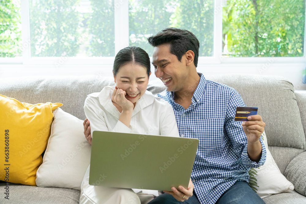 Fototapeta premium Happy Asian couple use credit card for online shopping at home