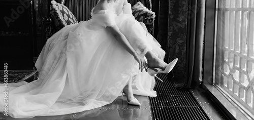 without a face. A bride in a fluffy wedding dress puts on shoes. 