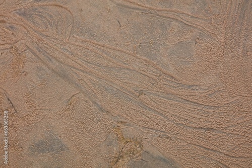 Abstract patterns on sand surface on the beach shore caused by waves washing over the sand.