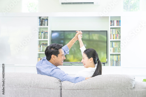 Rear of young couple relaxing and watching TV at home.