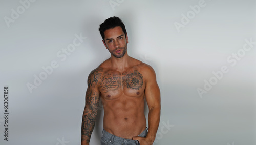 Shirtless muscular sexy male model, with empty copy space area for slogan, advertising or text message, against grey background.