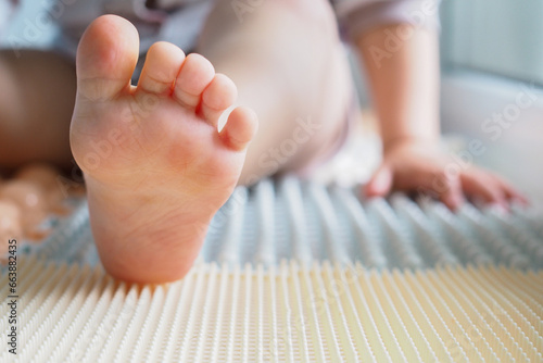 Toddler baby foot on a medical orthopedic colorful massage mat. Close up © Aisylu