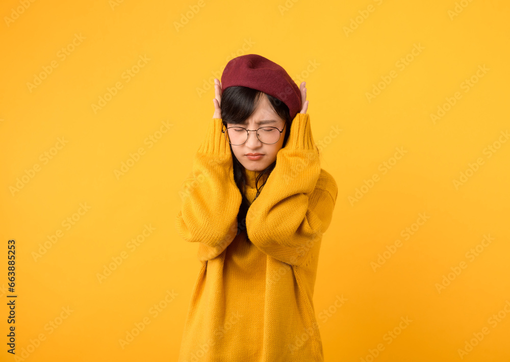 Noise stress getting to you. An upset lady, wearing a yellow sweater and red beret, seeks relief against a vibrant yellow backdrop. Noise stress getting to you. An upset lady, wearing a yellow sweater and red beret, seeks relief against a vibrant yellow backdrop.