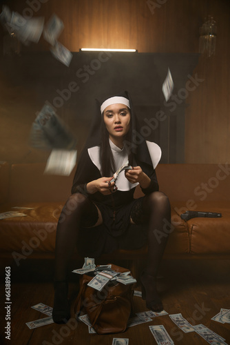 Young nun stripteaser dancer counting money sitting under dollar banknote rain