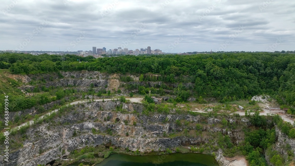 Abandoned quarry at mining operation with Richmond, VA city skyline on landscape horizon under partly cloudy sky
