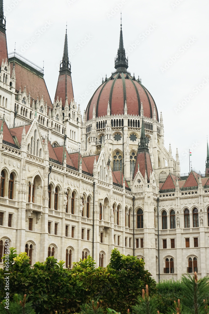 View of the Parliament building in Budapest against the backdrop of green bushes