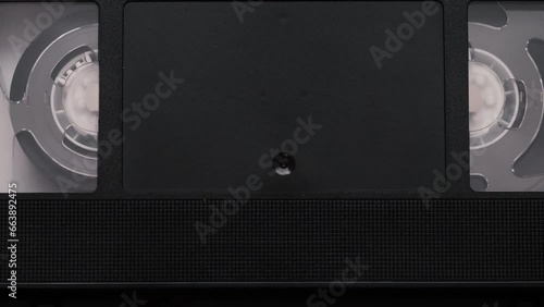 VHS videocassette is put into the video recorder to watch the video, another video cassette is on the video-tape recorder.