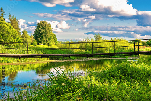 Summer sunny landscape with river and suspension bridge