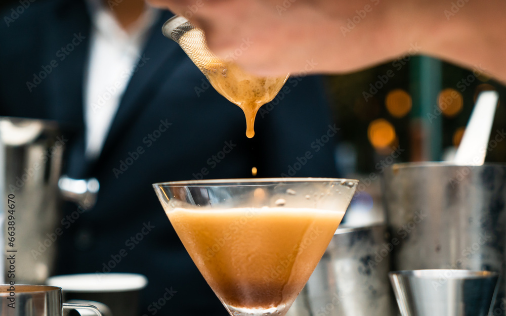 Bartender pouring alcoholic coffee cocktail. Cocktail dropping in glass. Serving summer cocktail in bar.	
