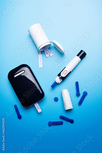 Diabetes awareness concept of glucose meter test strips and lancets on blue background flat lay. Diabetes awareness concept.