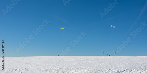 Kitesurfing in the snow with a blue sky