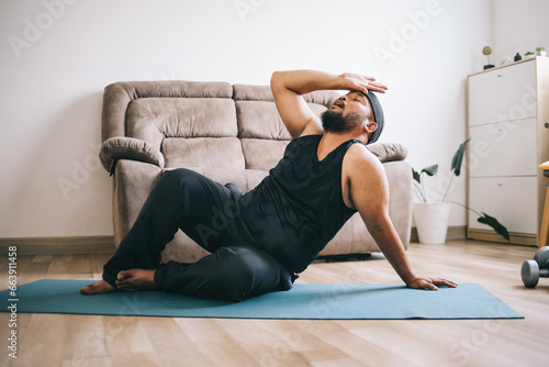 A fat man in sportswear feeling tired after practicing yoga