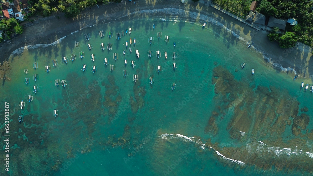 Aerial view of fishing boats parked off the shore of the tropical island of Bali. Colorful fishermen's boats near the beach, top-down view. Adventure and travel concept.