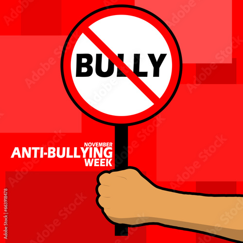 A sign prohibiting bullying is being held in a hand, with bold text on red background to commemorate Anti-Bullying Week on November