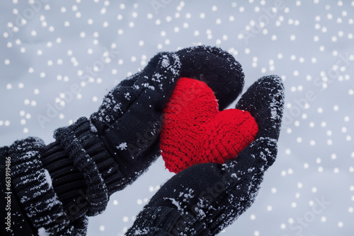 girl in gloves holding a red toy heart in winter weather. AI GENERATE
