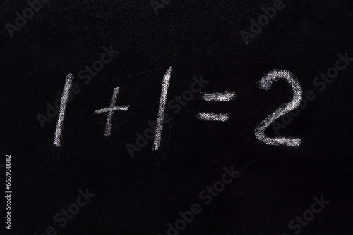 Simple math equation 1 1 2 written school board chalk. Blackboard equations one plus one equals two written black board background. 1 plus 1 equals 2 writing chalkboard background. Elementary school