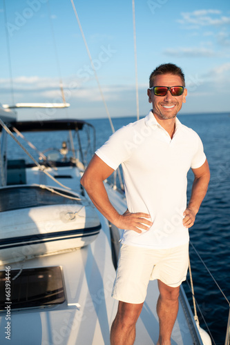 Confident handosme man in sunglasses on a yacht photo