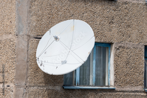 Satellite TV antenna on the wall of the house. Round white antenna receiver for radio signal. City antenna for television  radio  Internet