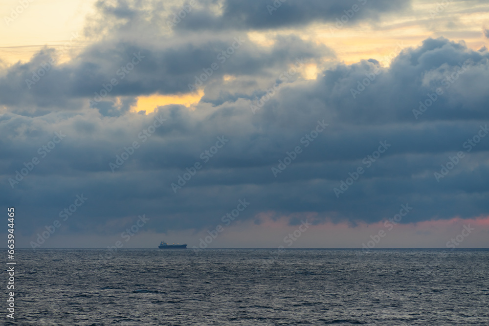 Seascape in the Baltic Sea at sunset.  A cargo ship at sea, the sky is overcast.