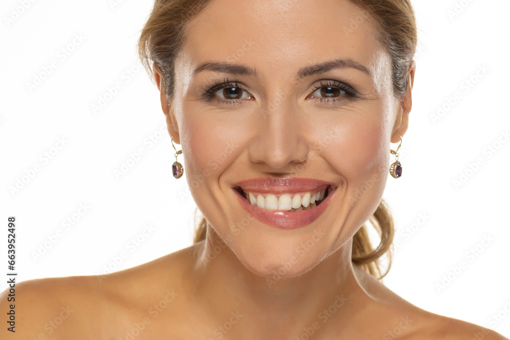 A portrait of a joyful smiling woman with a beautiful helthy teeth and tasteful makeup, biting her lips on a white background A portrait of a joyful smiling woman with a beautiful helthy teeth and tasteful makeup, biting her lips on a white background