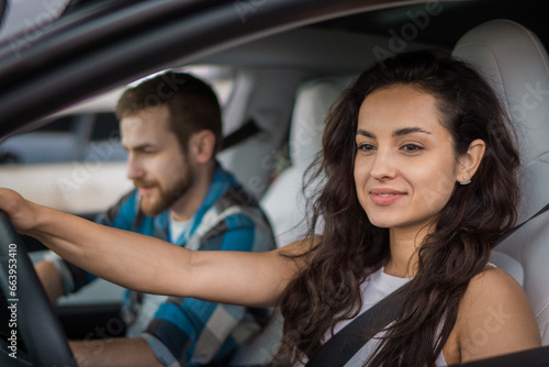 Smiling couple enjoying summer trip. Woman driving a car with his boyfriend on passenger seat. Travel adventure drive, happy summer vacation concept