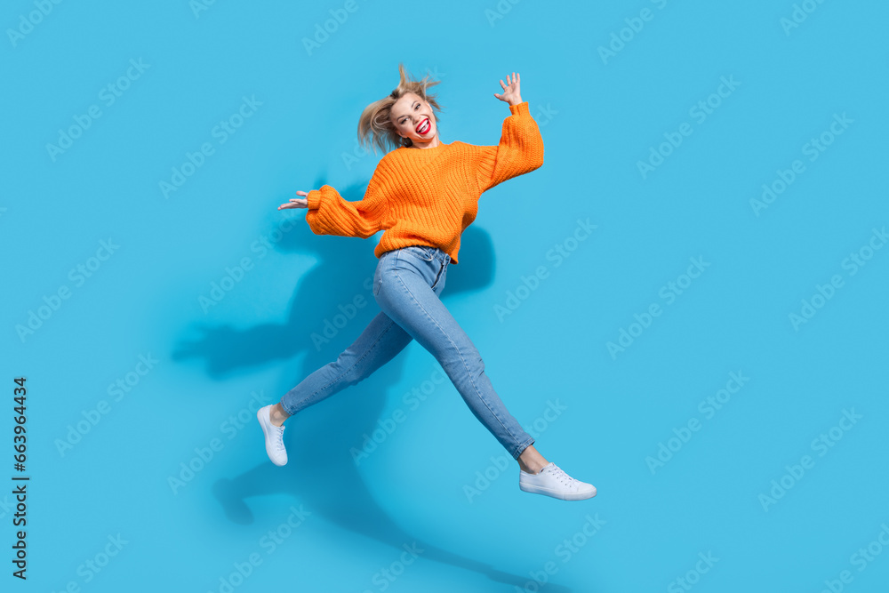 Full length profile photo of lovely overjoyed person jump rush empty space isolated on blue color background Full length profile photo of lovely overjoyed person jump rush empty space isolated on blue color background