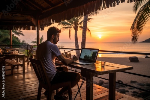 Digital nomad working remotely at a beach cafe during sunset.