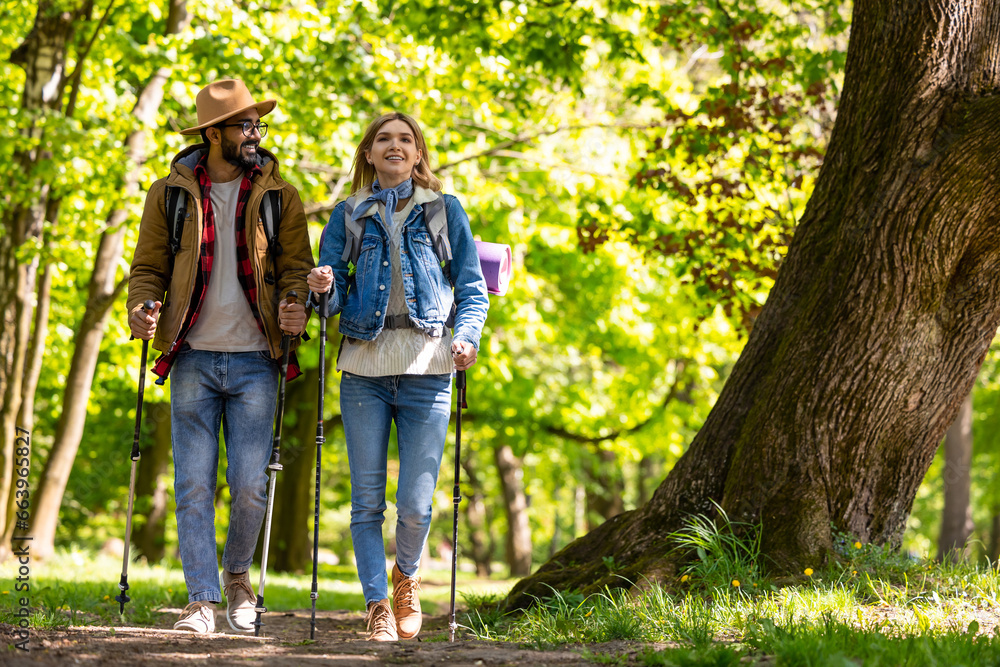 Obraz premium Young couple with scandinavian sticks walking and talking