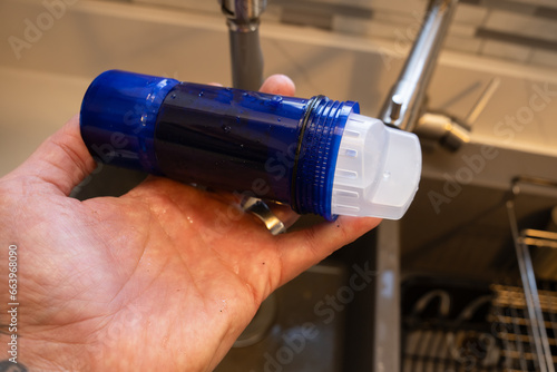 hand holds a new water filter cartridge that is ready to install and filter lead and other wastes from drinking water