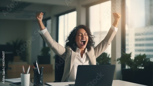 Successful businesswoman raises her hands up rejoices in increasing profits in business. Businesswoman is receiving good news online, raising her hands and showing her fists.