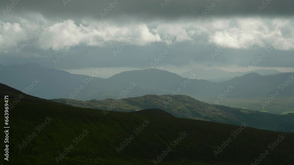 A green mountain range under a cloudy, gray sky, taken from a high vantage point. A green mountain range under a cloudy, gray sky, taken from a high vantage point.