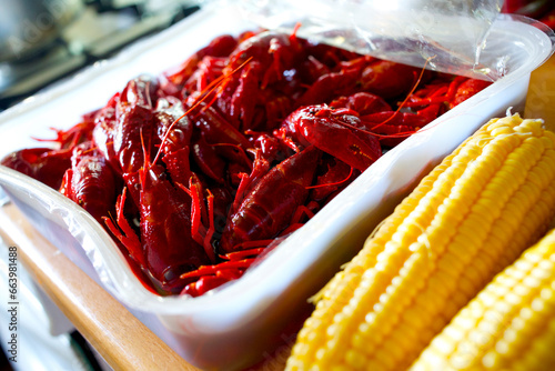 Louisiana crawfish in a tupperware container next to corn ready for seafood boil photo
