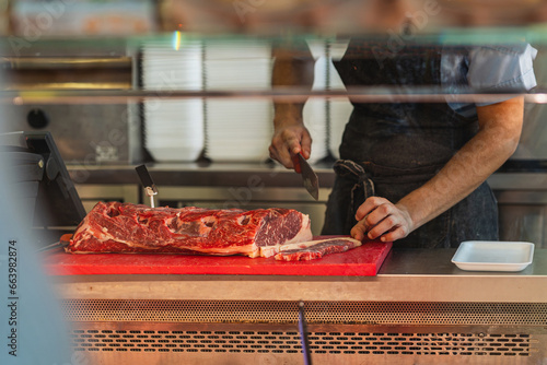Un macellaio affetta una costosa bistecca dietro il banco di una macelleria. photo