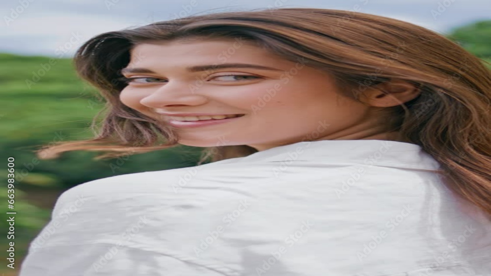 Portrait gorgeous model looking camera over shoulder in green hills vertically.