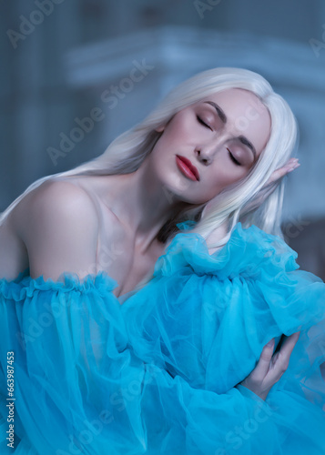 Beautiful woman with a elegant curly hairstyle. Princess. A luxurious blue dress with a long train