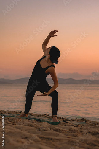  young girl practicing yoga at the beach at sunrise