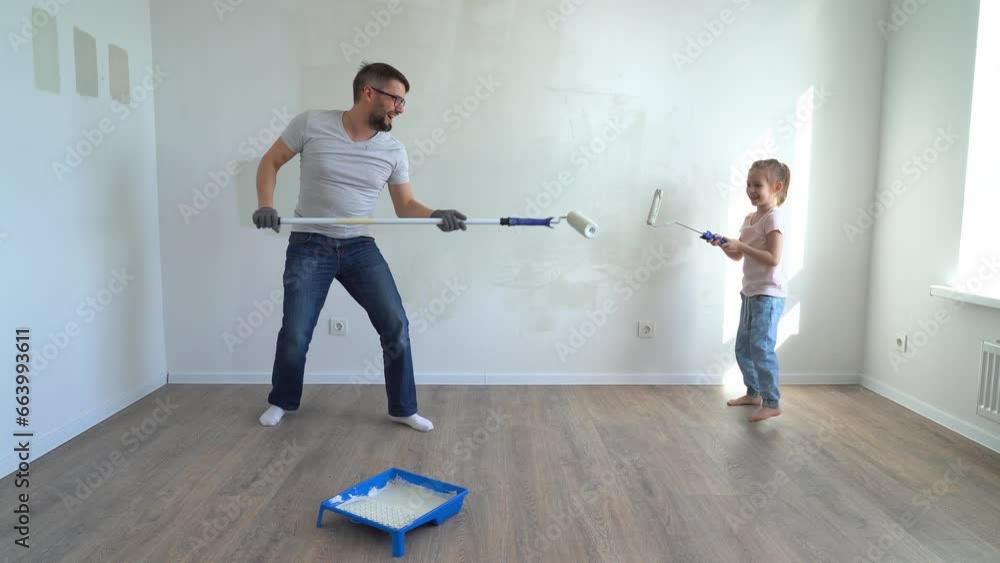 Father and little daughter fun fight with roller and laugh painting ...